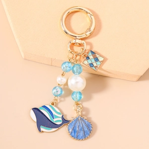 Porte-clés doré thème marin avec baleine, coquillage, perles bleues et perles blanches