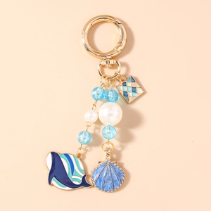 Détail des breloques baleine et coquillage sur porte-clés doré avec perles bleues