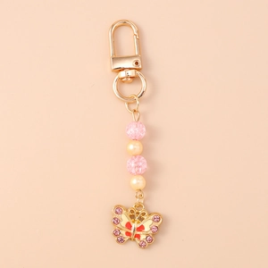 Detail van vlinder sleutelhanger met roze kralen, strass en gouden karabijnsluiting