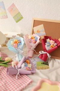 Detail showing four colors of mini handmade crochet flower bouquets in gift packaging