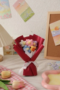 Close-up of handmade knitted mini flower bouquet with colorful yarn and red paper wrap