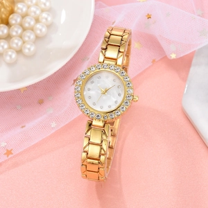 Close-up of gold women watch with rhinestone bezel and mother of pearl dial on pink background