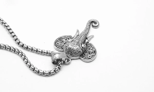 Detailed macro view of vintage elephant head pendant with intricate tribal carvings and box chain