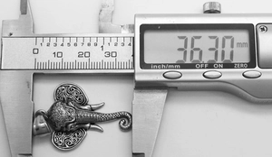 Macro shot of retro elephant pendant size measurement showing 36.30mm width on caliper