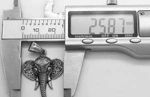 Macro view of retro elephant pendant showing width measurement of 25.87mm on calipers