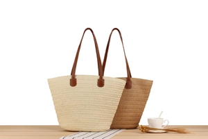 Close-up of woven paper rope straw tote bags in beige and light brown with leather handles