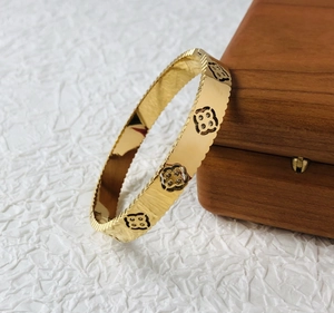 Detailed view of golden wave-edge bangle with sparkling clover-shaped crystal inserts