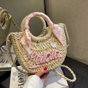 Handmade woven straw half-moon bag with pink embroidery and silk scarf handle decor