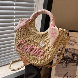 Straw half-moon bag with pink Lola embroidery and floral scarf on the handle