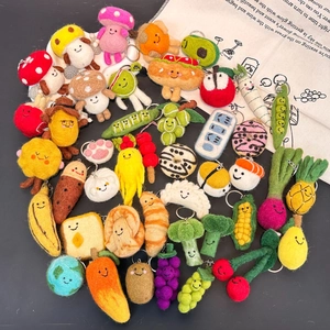 Handmade wool felt fruit and vegetable keychains with cute smiling faces on grey background