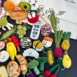 Detailed flat lay of colorful handmade wool felt fruit and vegetable keychain charms