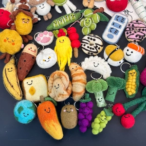 Macro shot of assorted handmade wool felt fruit and vegetable keychains with smiling faces