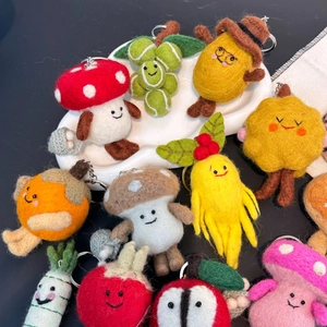 Macro detail of handmade wool felt keychains featuring cute fruit and vegetable characters