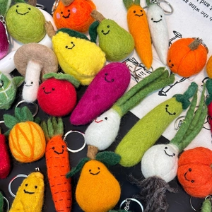 Flat lay of handmade wool felt fruit and vegetable keychains with cute faces
