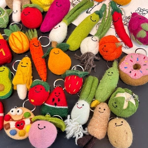 Flat lay of handmade wool felt keychains featuring cute smiling fruits and vegetables