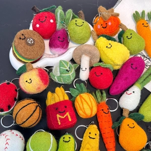 Detailed macro view of handmade wool felt keychains featuring fruit and vegetable designs