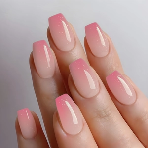 Macro detail of long coffin nails with pink ombré gradient and fine glitter finish
