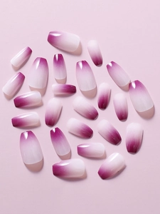 Detail of glossy purple ombré coffin-shaped press-on nails on a soft pink surface