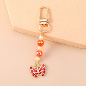 Detailopname van kralen vlinder sleutelhanger met rode strass en imitatieparels