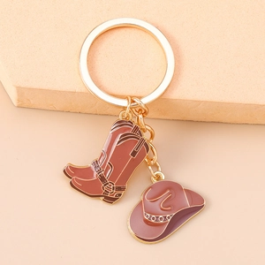 Détail d'un porte-clés doré avec charms de botte et chapeau de cow-boy en émail marron