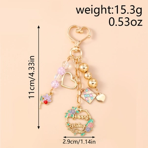 Detailed view of beaded keyring with hollow heart and Happy Holidays floral wreath charm