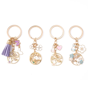 Set of four Chinese style keychains with enamel rabbits, flowers and tassels on white background