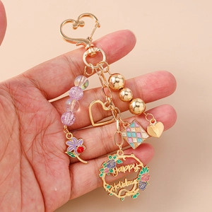 Golden heart keychain with purple beads and Happy Holidays floral wreath pendant