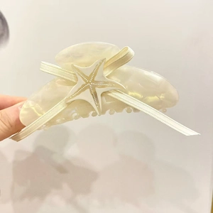 Détail d'une pince à cheveux étoile de mer en acétate avec un élégant nœud en ruban