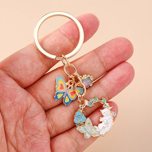 Detail of floral rabbit keychain featuring enamel butterfly and cat charms held in hand