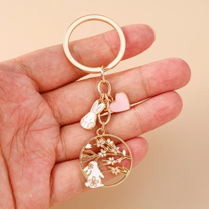 Detailed close-up of golden rabbit keychain with enamel cherry blossom and heart pendant
