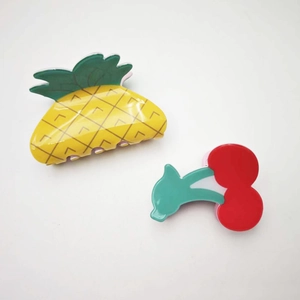 Dettaglio macro delle mollette per capelli in acrilico a forma di ananas e ciliegia