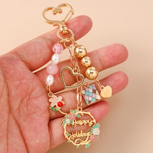 Golden Happy Holidays keychain with floral wreath, beads and hollow heart charm