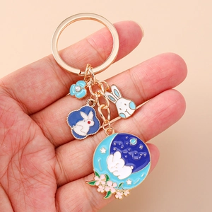Detail of bunny charm keychain with blue floral and moon enamel pendants on gold chain