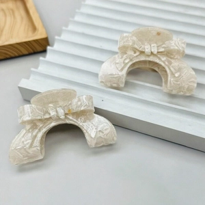 Elegant French style bow-shaped PVC hair claws with cream marble texture in a set of two