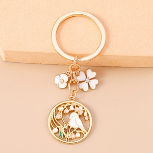 Detailed view of bird and plum blossom pendant with floral charms on golden keychain