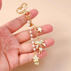 Close-up of golden keychain featuring star heart pendants and white faux pearls