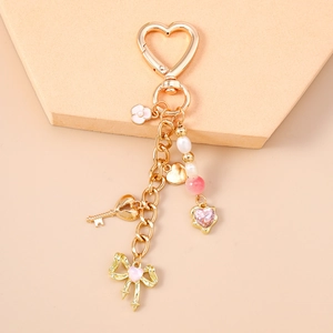 Close-up of golden heart-shaped keychain with pink enamel flower and beaded star charms