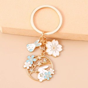 Detail of a gold plated keychain with a white rabbit, cherry blossom and enamel round pendant