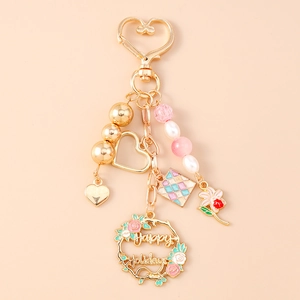 Macro view of golden keychain with heart charms, pearl beads and Happy Holidays floral ring