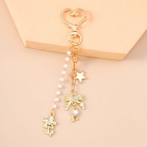 Detail of a gold-tone keychain with faux pearls, rhinestone bow, and colorful heart charm