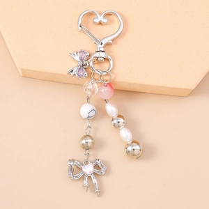 Detailed view of silver-beaded keychain with purple bow and heart clasp on warm steps