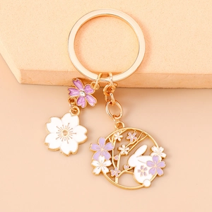 Detailed close-up of enamel cherry blossom and rabbit charms on a gold keychain