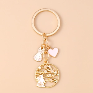 Detail of a golden keychain featuring a white rabbit, cherry blossoms, and pink heart charm