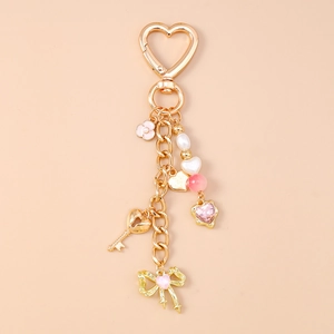 Detail of golden heart keychain with pink heart gems, pearls and bow pendant charms