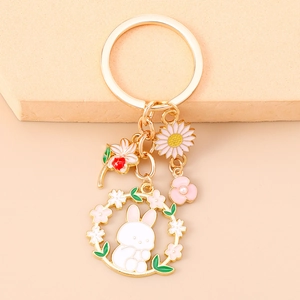 Detail of golden enamel keychain set with pink flower, bunny and sunflower charms