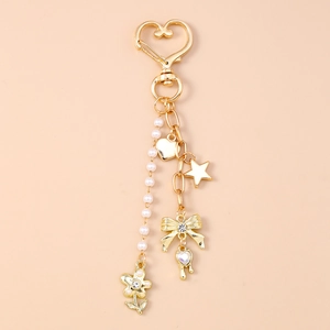 Detail of golden heart clasp keychain with pearls, star, and rhinestone bow charm