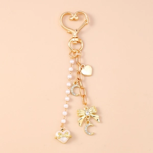 Detail of a gold-tone heart keychain featuring faux pearls, moon, and rhinestones
