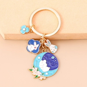 Detailed macro view of enamel rabbit and flower pendants on a gold-plated keychain