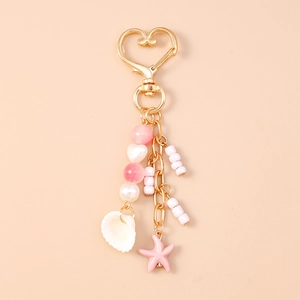 Detail of beaded keychain with pink starfish, seashell, and golden heart carabiner