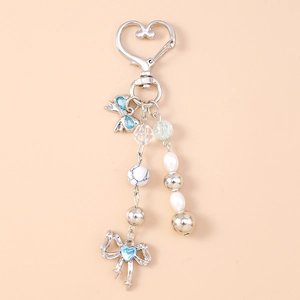 Detail of beaded keychain with blue rhinestone bow charm and heart-shaped silver clasp